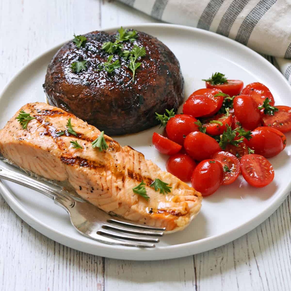 Grilled salmon is served with a grilled portobello mushroom and tomato salad.