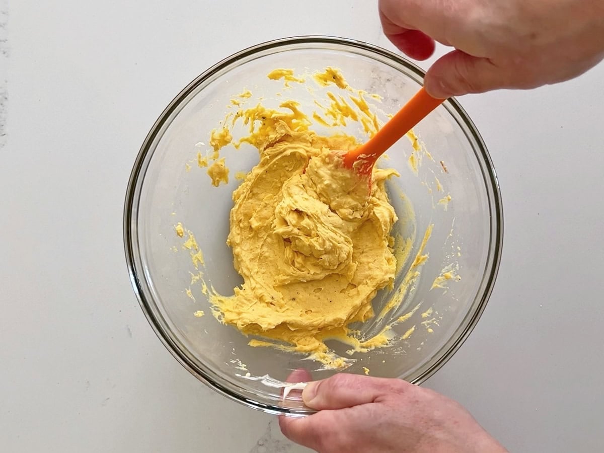 Mixing the yolks with the condiments.