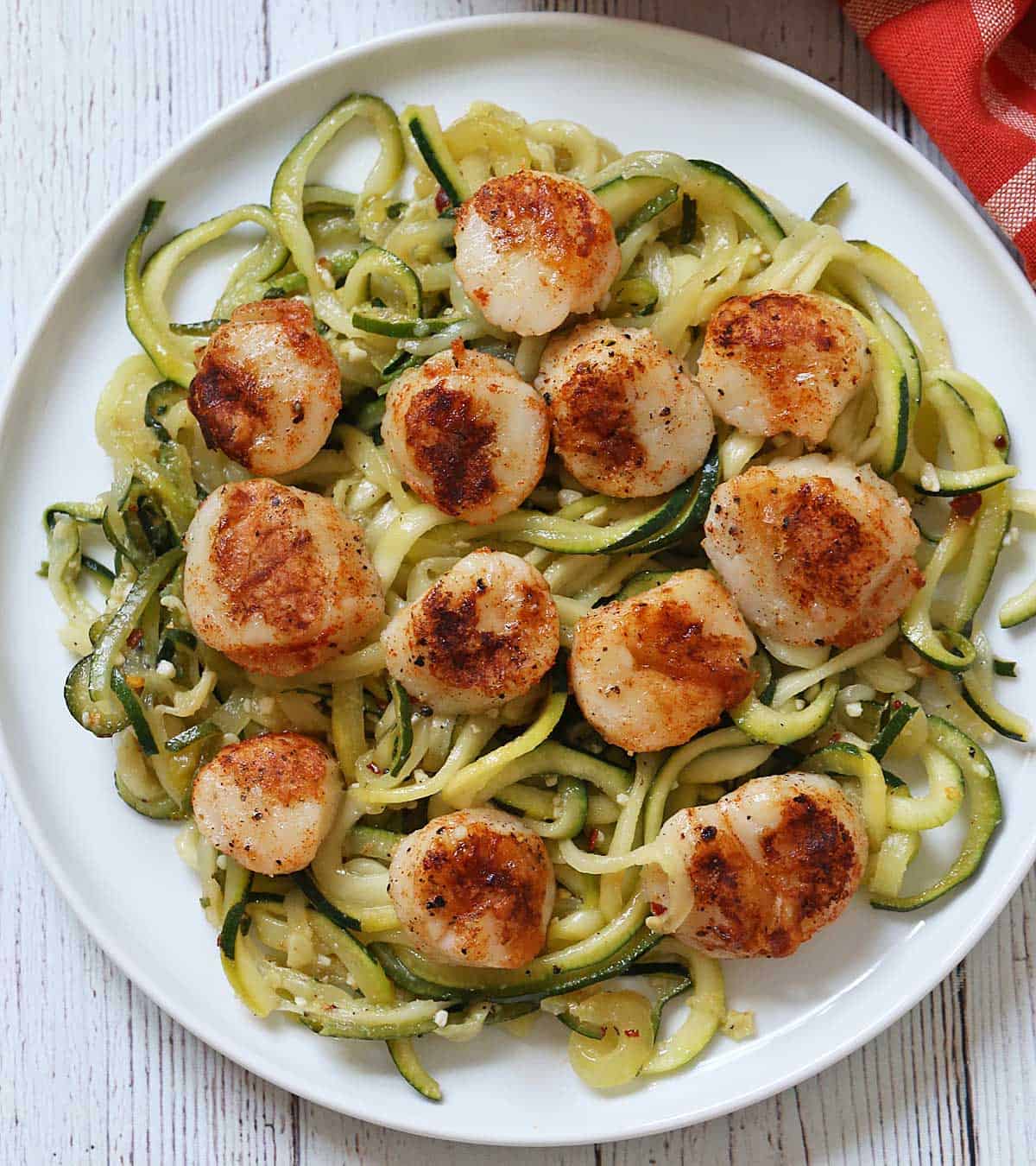 Grilled scallops are served on a bed of zucchini noodles.