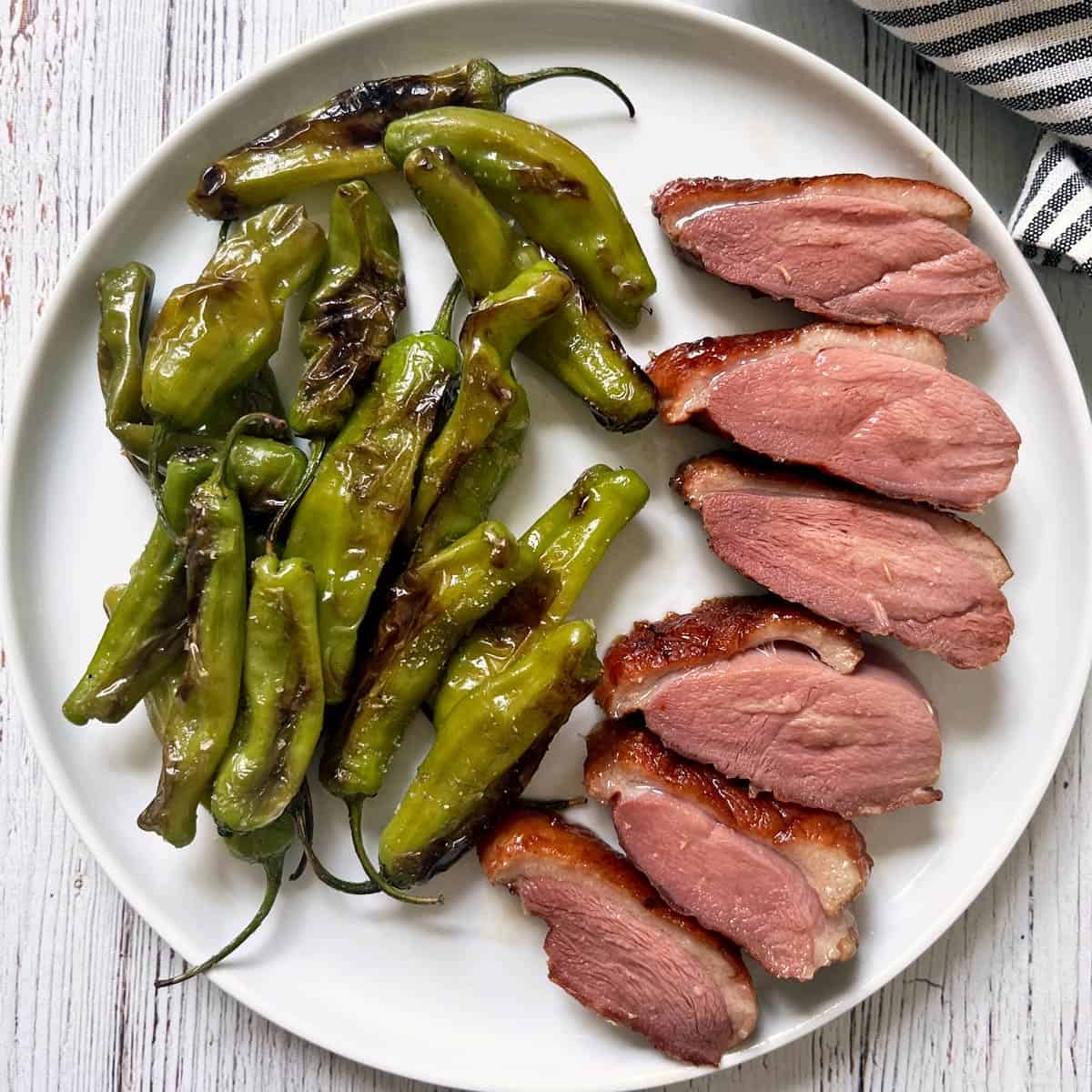 Shishito peppers are served as a side dish to duck breast.