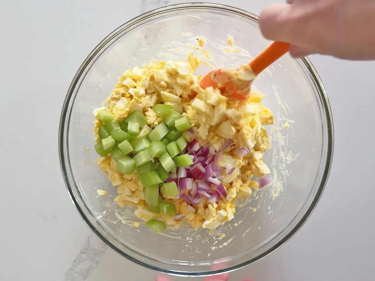 Adding celery and onions to the salad.