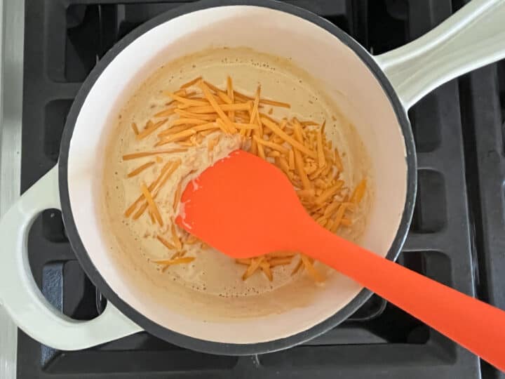 Adding cheese to the heavy cream mixture.