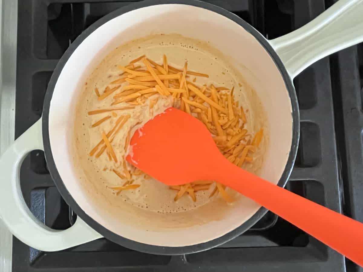 Adding cheese to the heavy cream mixture.