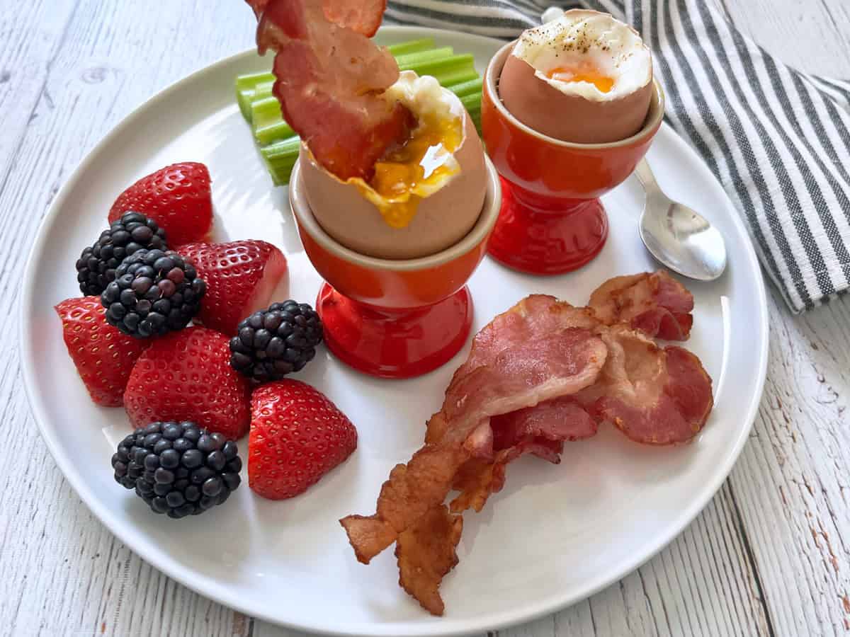 Bacon is dipped into a soft-boiled egg.