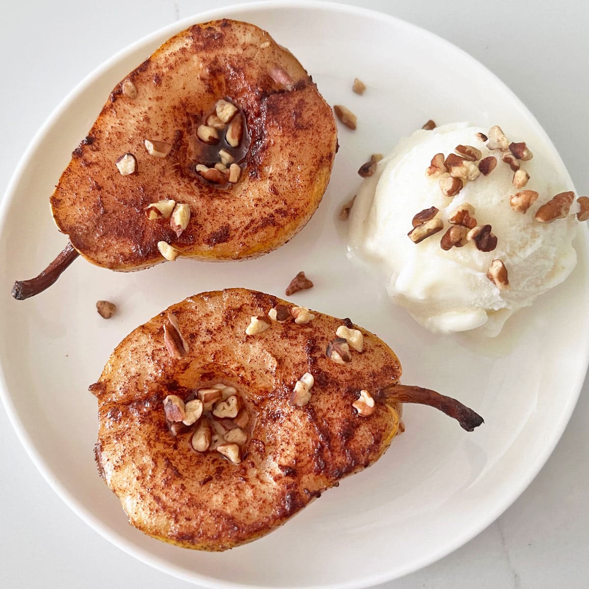 Baked pears are served with frozen yogurt and nuts.
