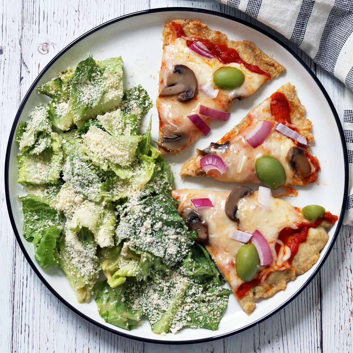 Caesar salad is served with pizza.