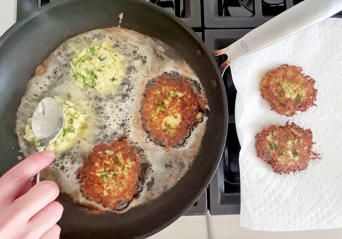 Adding more fritters to the skillet.