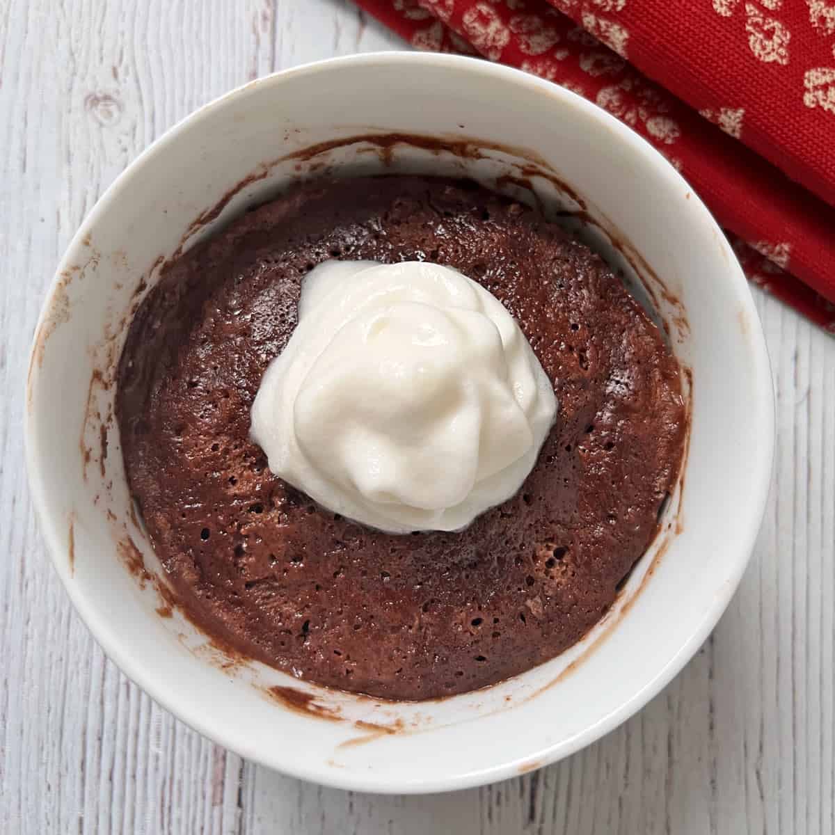 Chocolate mug cake is served with whipped cream.