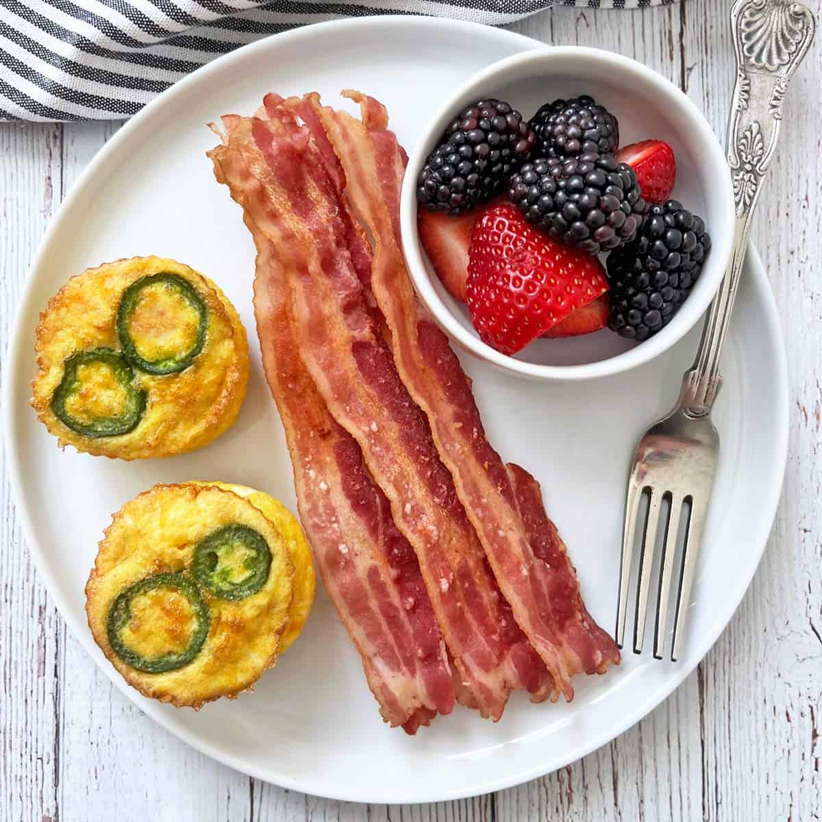 Egg muffins are served with microwave bacon and fresh berries.