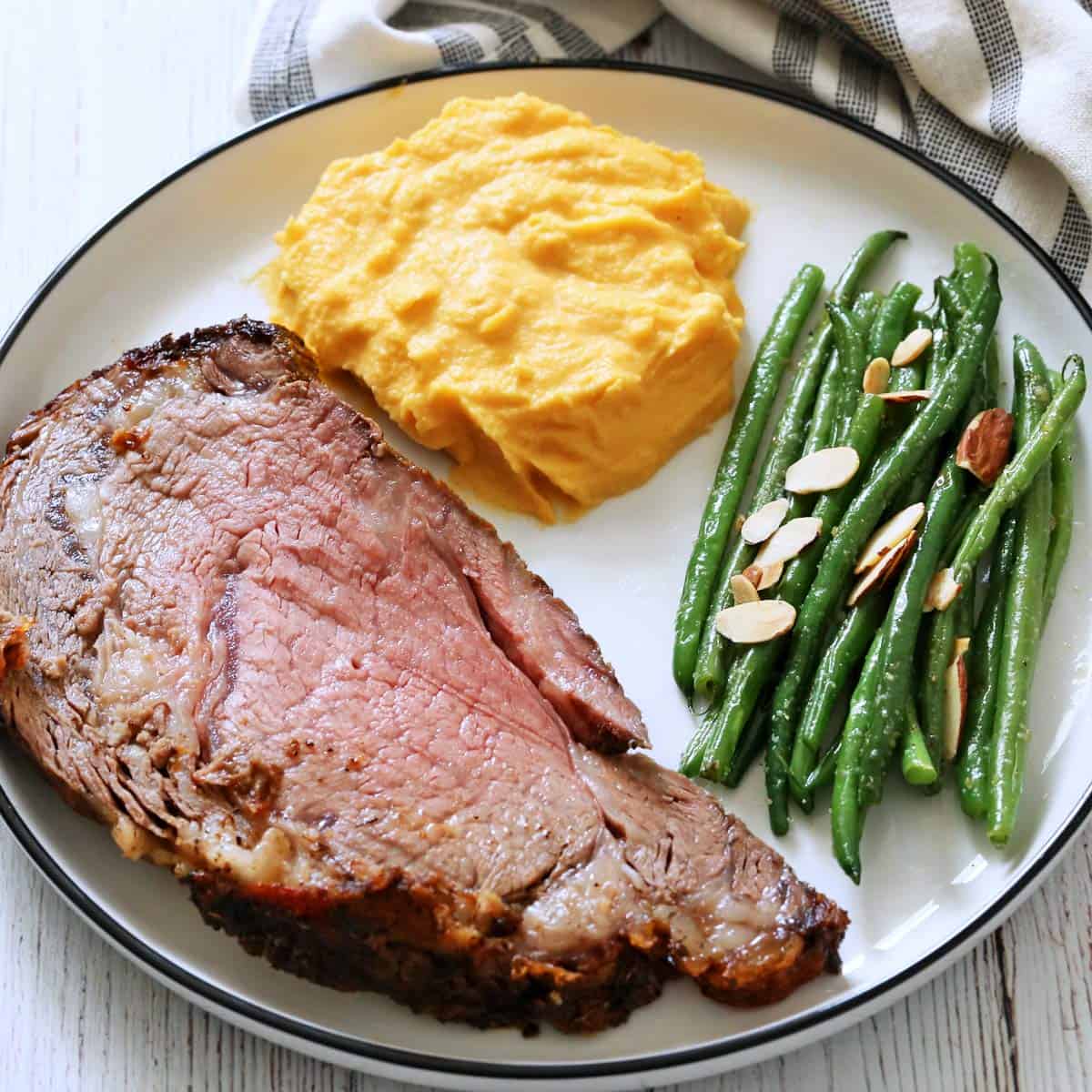 Green beans almondine are served with ribeye roast and mashed butternut squash.