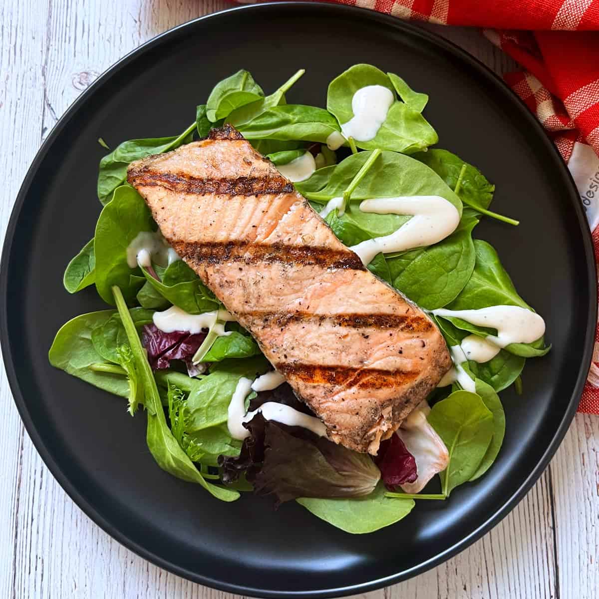 Leftover grilled salmon is served on top of a mixed greens salad.