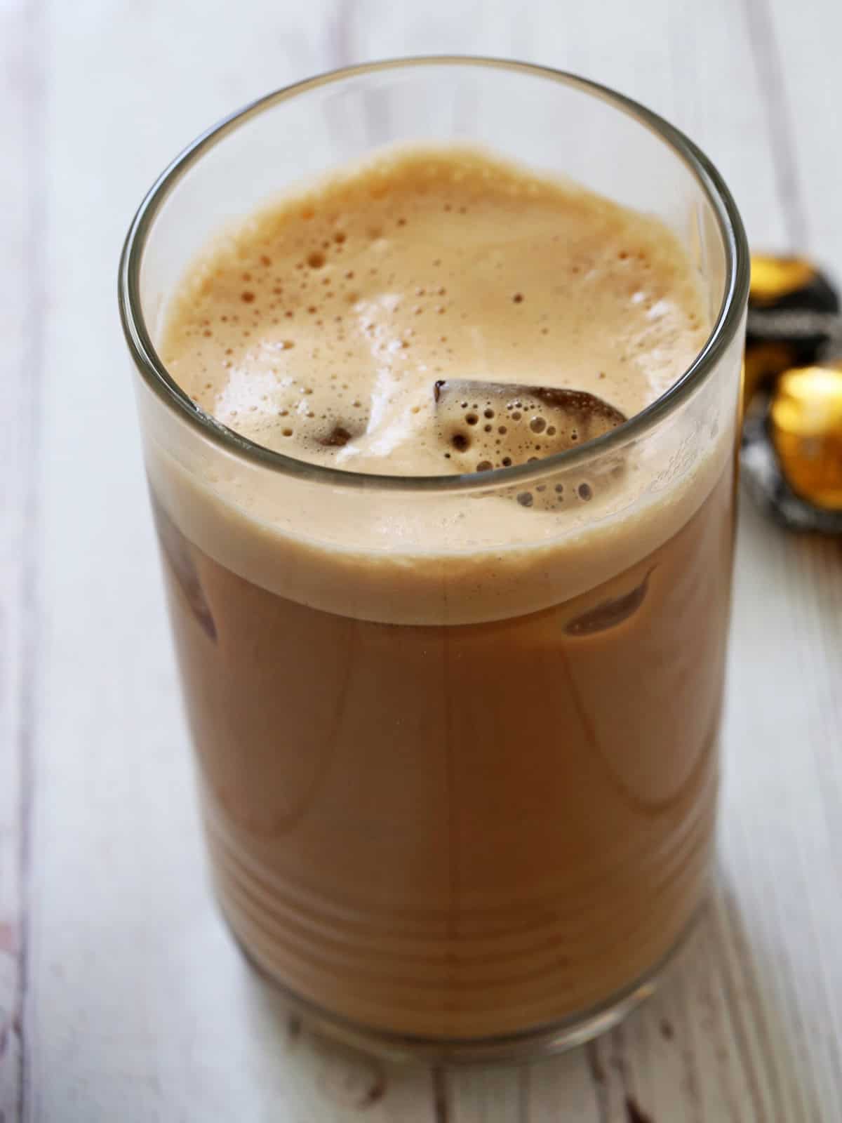 Iced coffee is served in a tall glass.