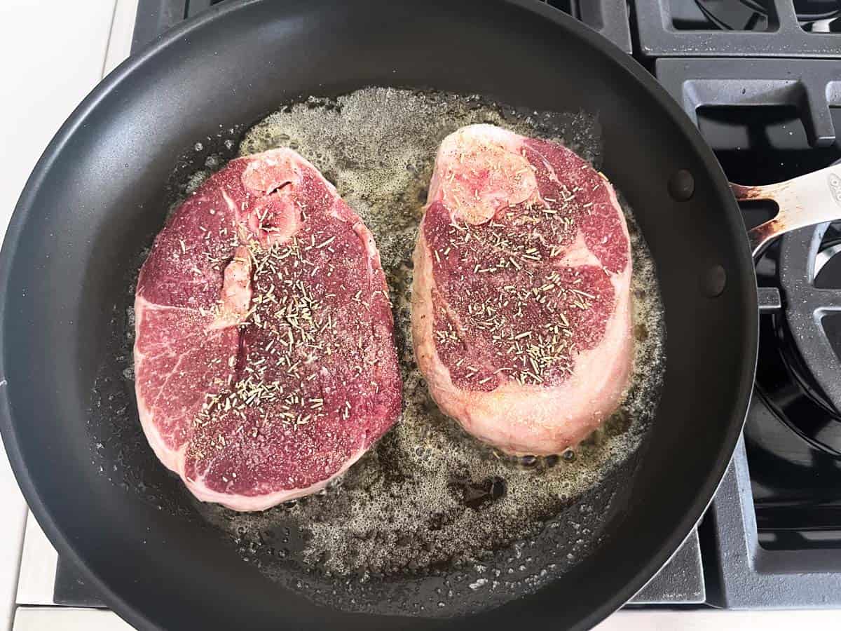 Cooking lamb steaks in butter in a nonstick skillet.
