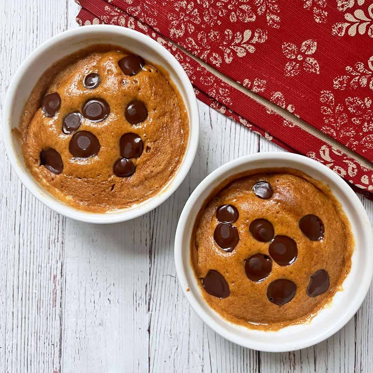 Two peanut butter mug cakes are topped with chocolate chips.