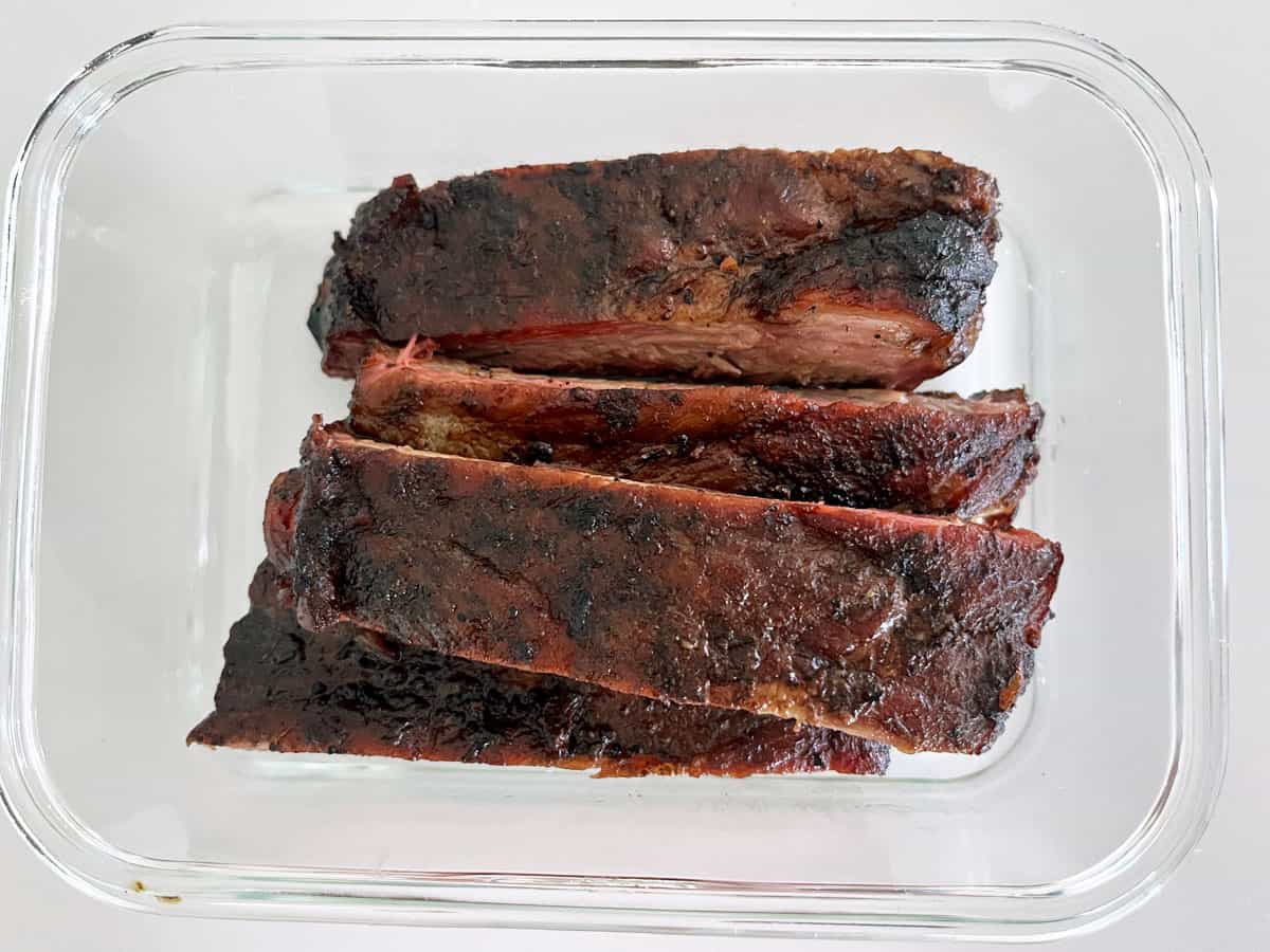 Leftover ribs are stored in a glass food storage container.