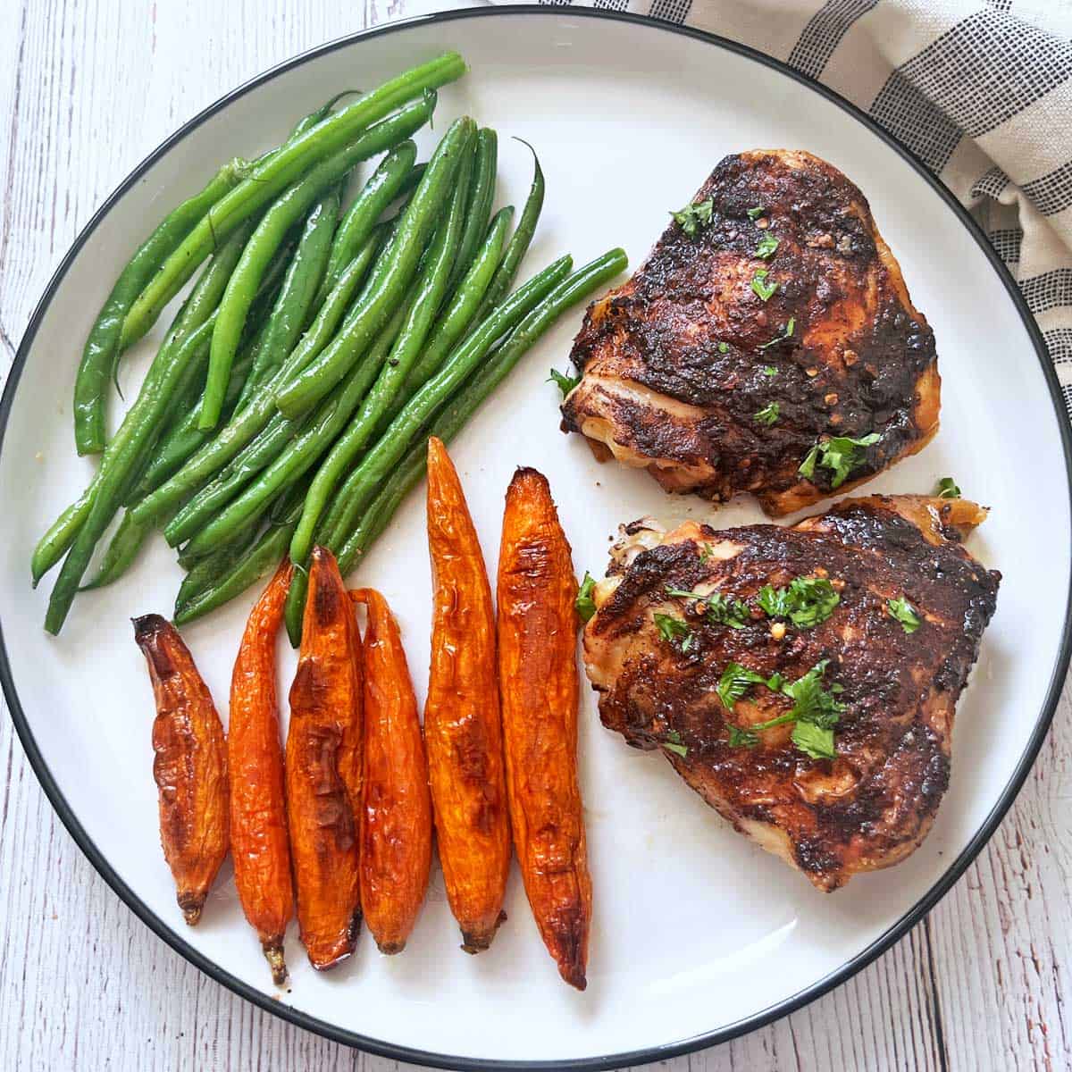 Roasted carrots and green beans are served as side dishes to jerk chicken.