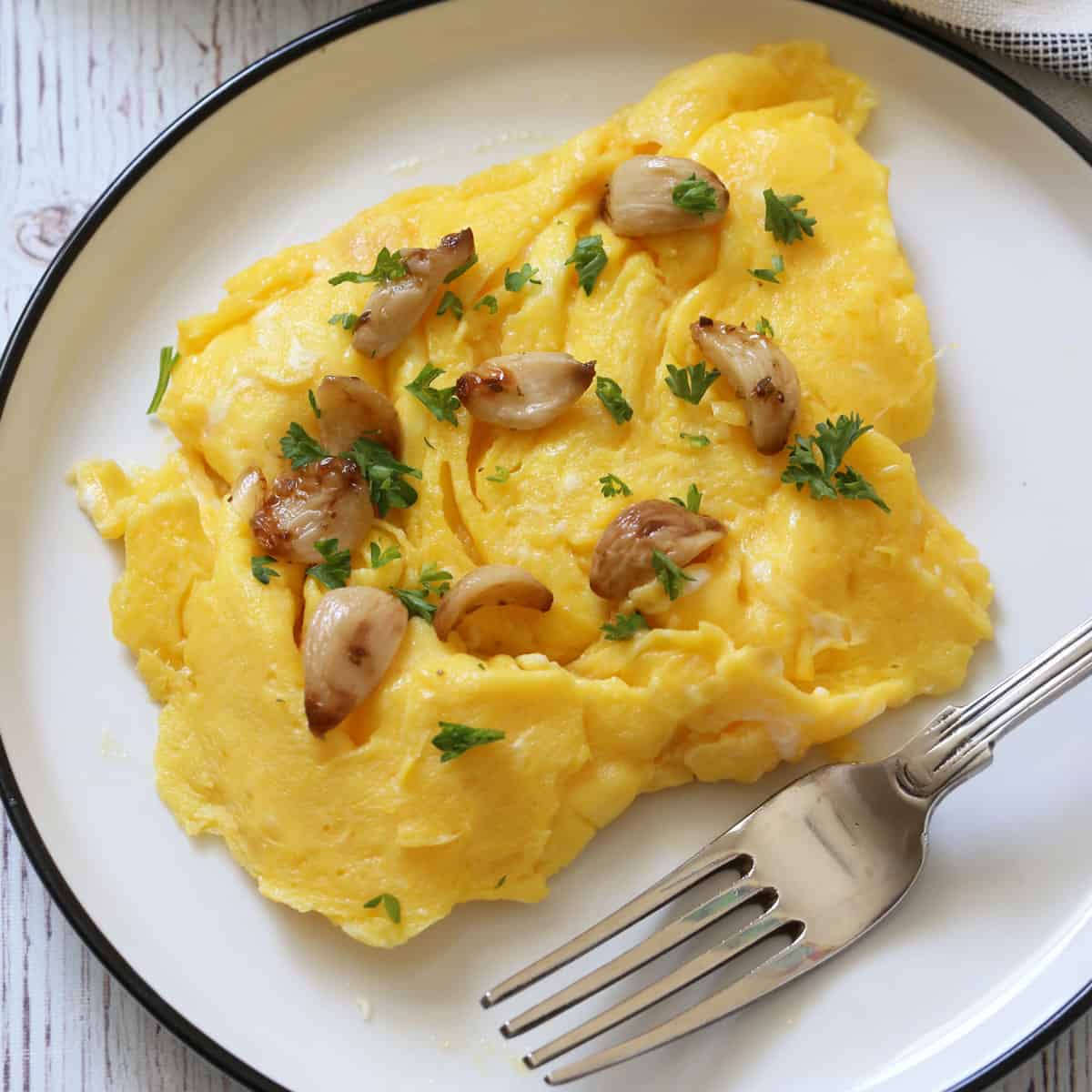 Scrambled eggs are topped with roasted garlic cloves.