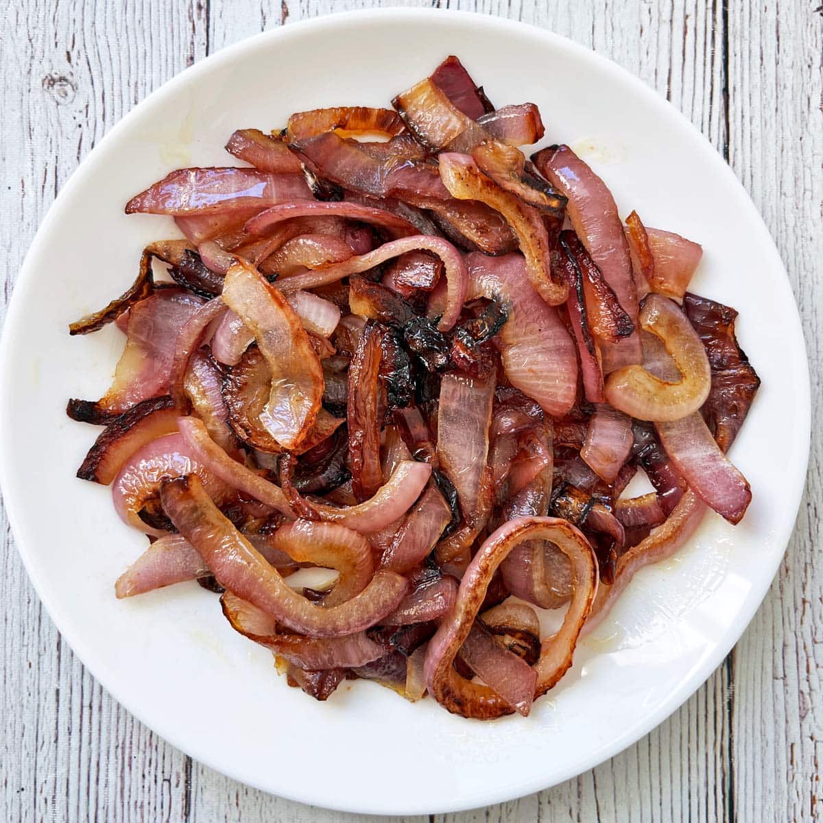 Sauteed red onions on a white plate.