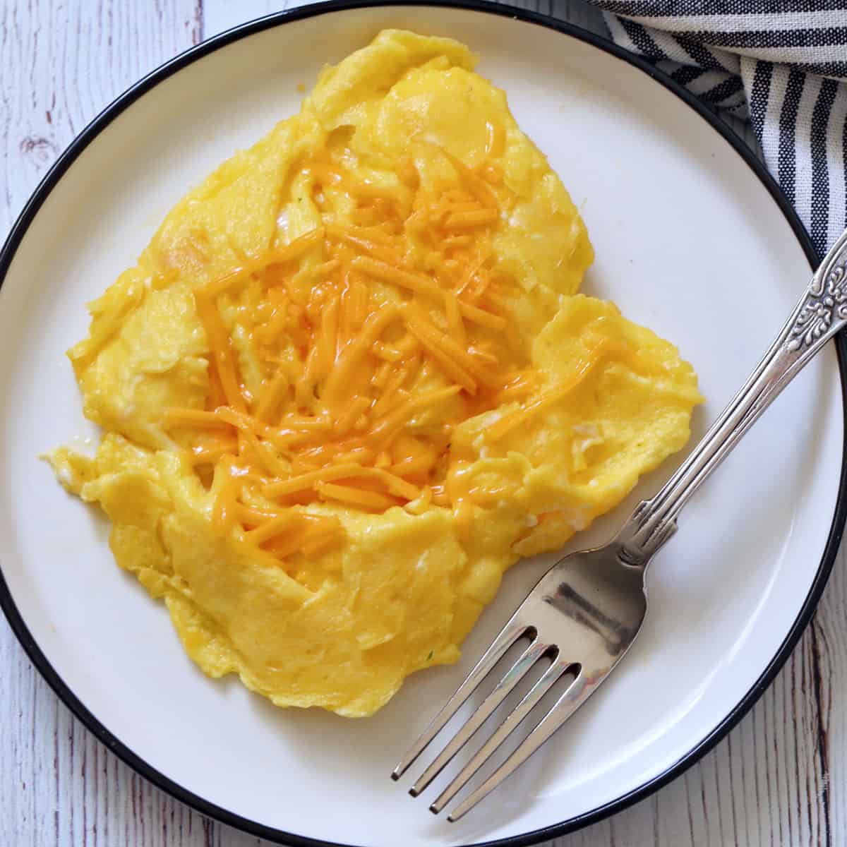 Scrambled eggs are topped with shredded cheese.