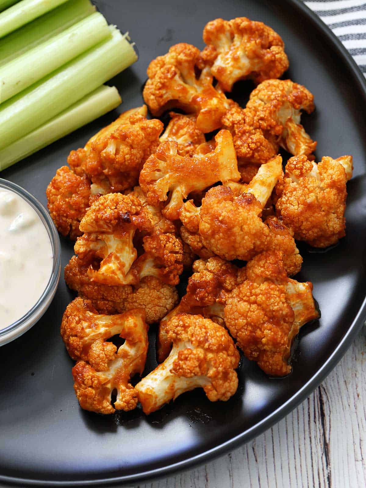 Buffalo cauliflower is served with celery sticks and blue cheese dip.