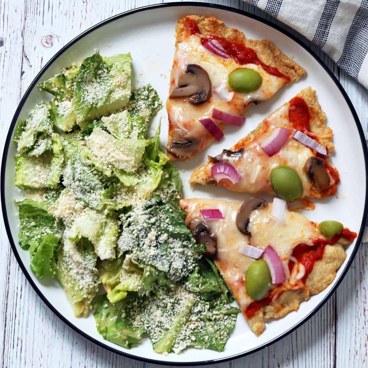 Chicken crust pizza is served with Caesar salad.