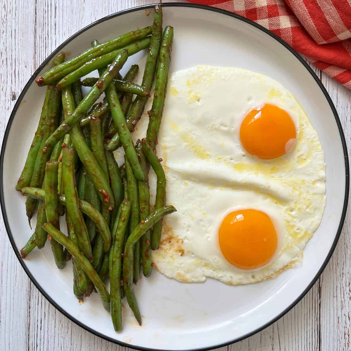 Leftover Chinese green beans are served with fried eggs.