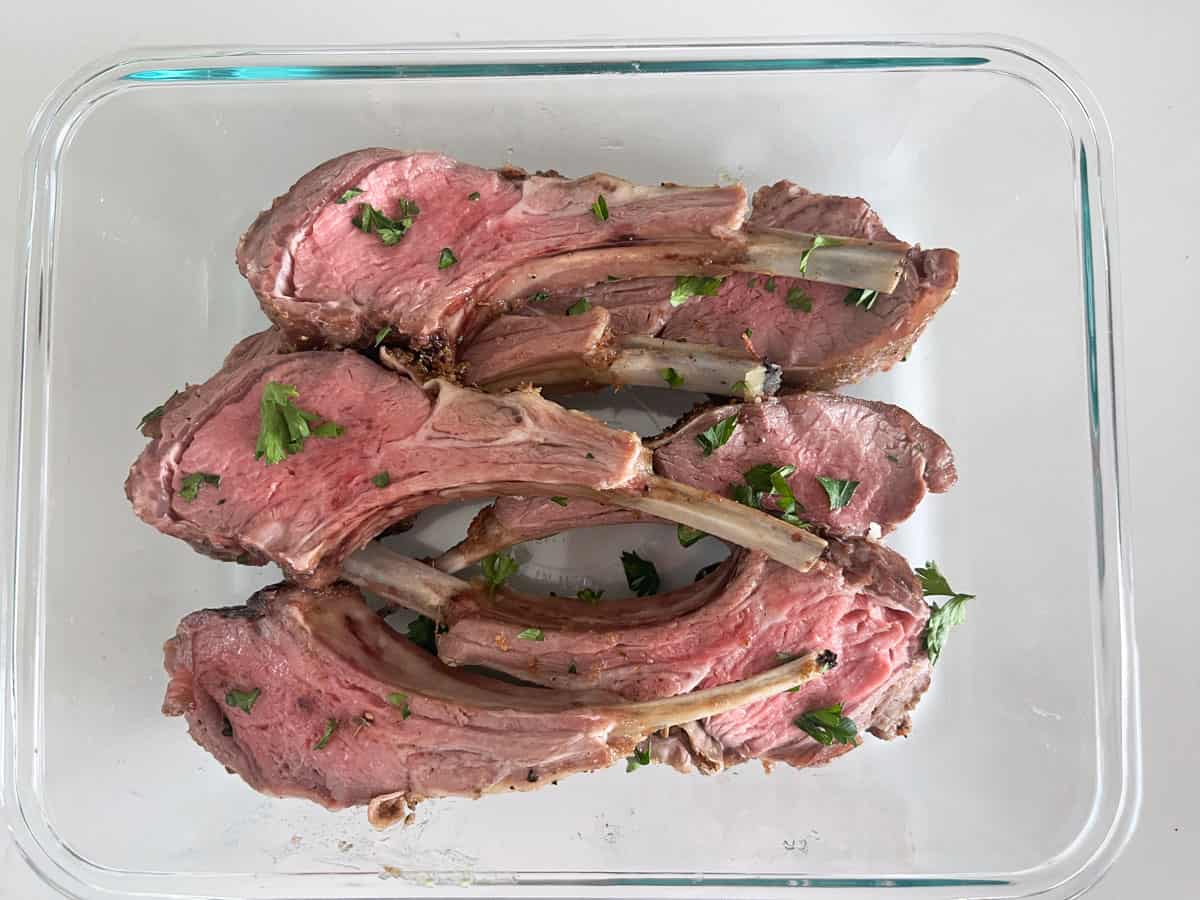 Ribs cut from a roasted rack of lamb are kept in a glass food storage container.