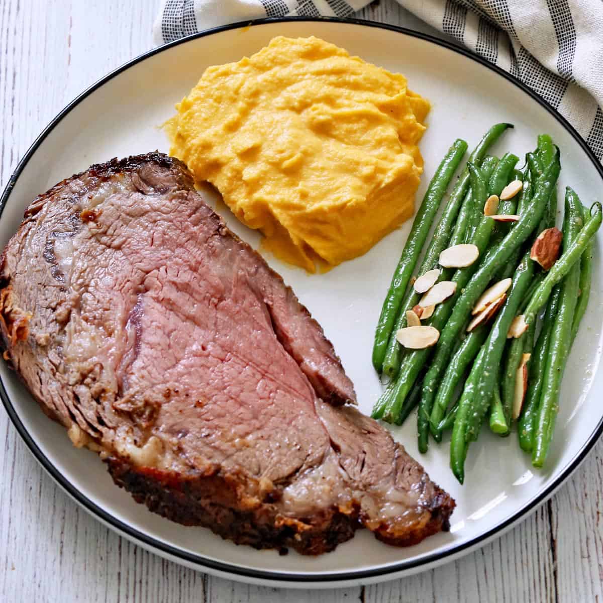 Ribeye roast is served with mashed butternut squash and green beans almondine.