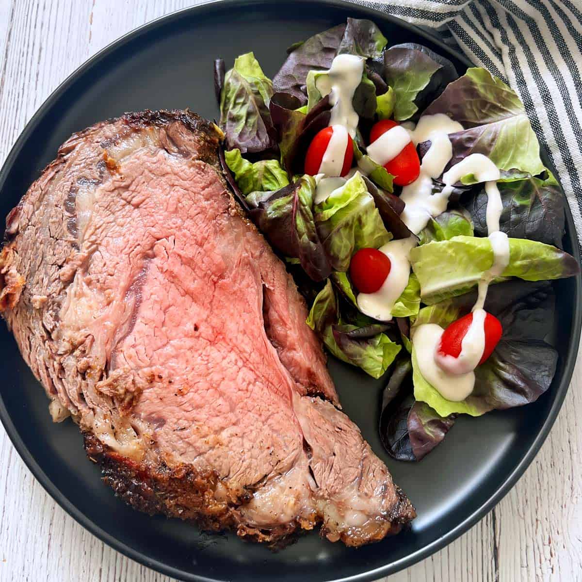 Ribeye roast is served with a lettuce and tomato salad.