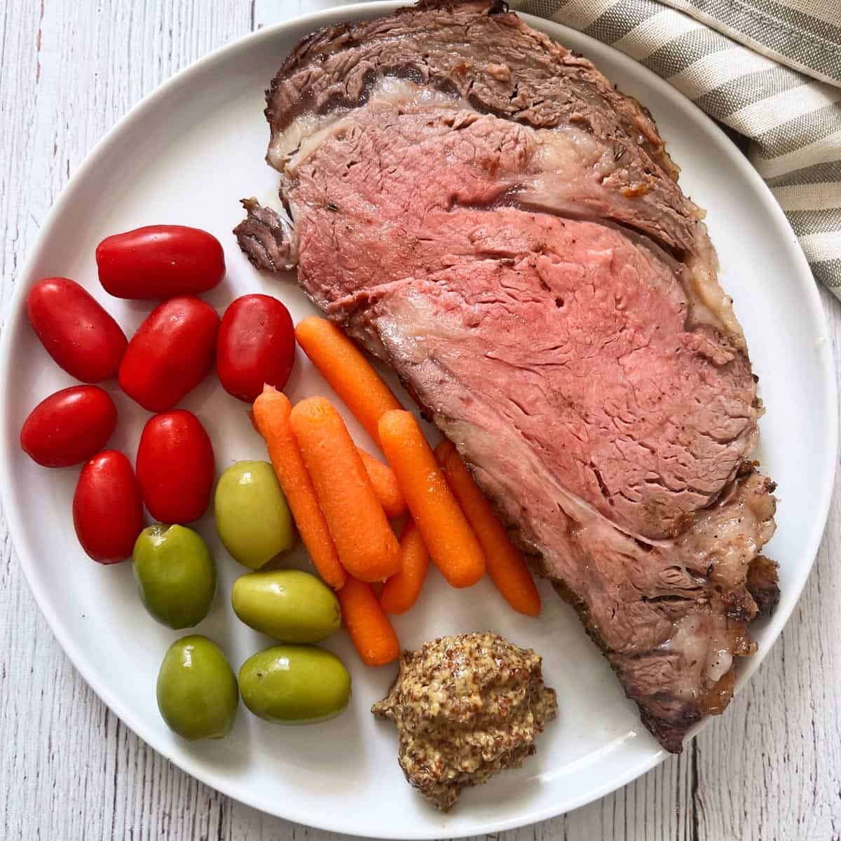 Ribeye roast leftovers are served with veggies, olives, and mustard.