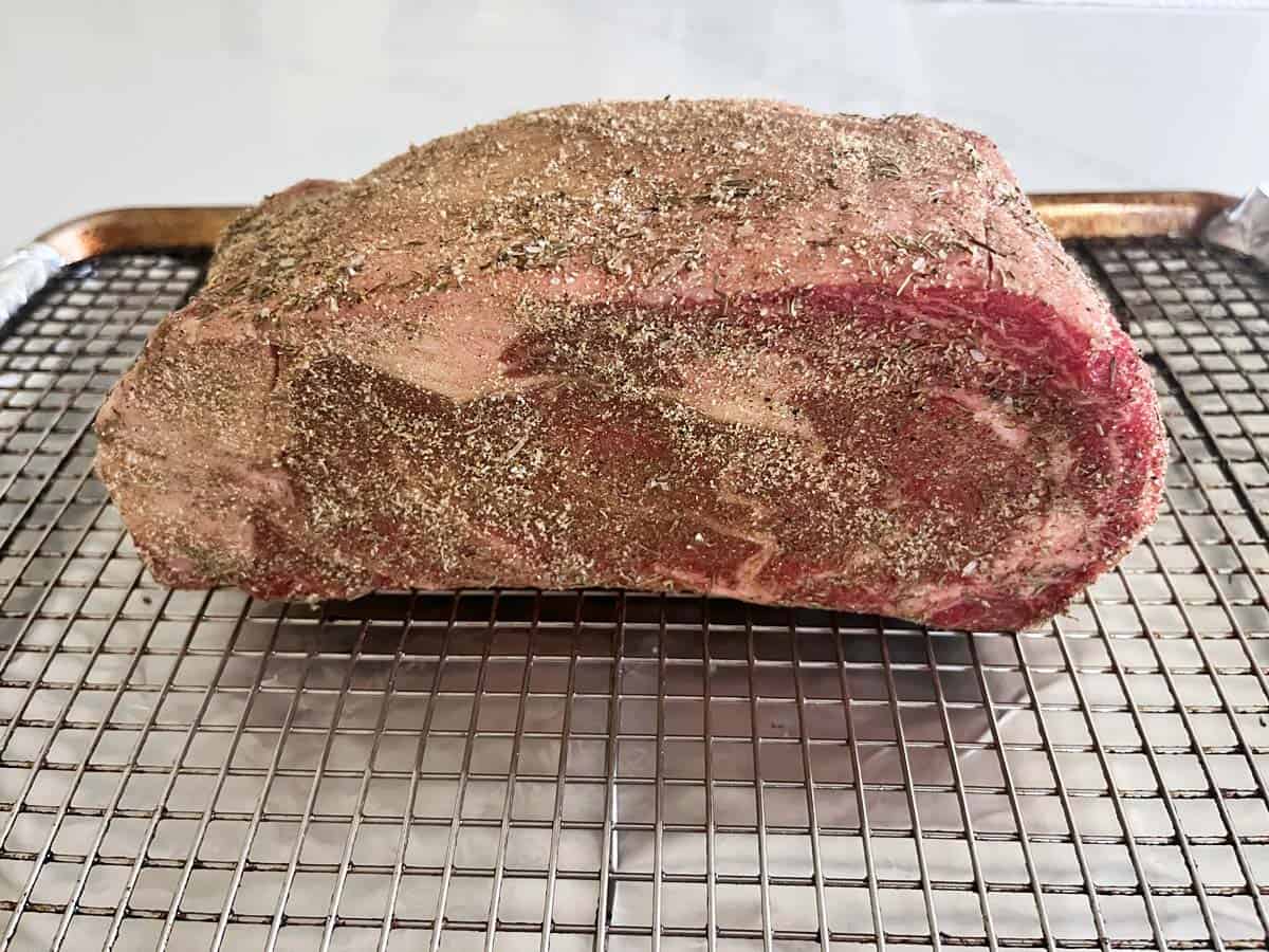 The seasoned roast is resting on the baking sheet.