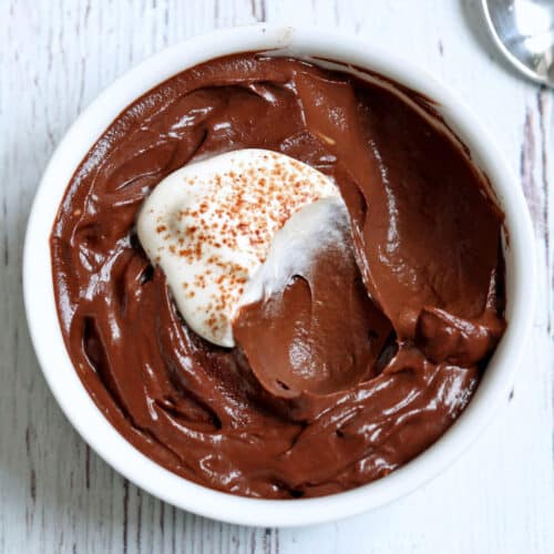 Avocado chocolate mousse is topped with whipped cream.