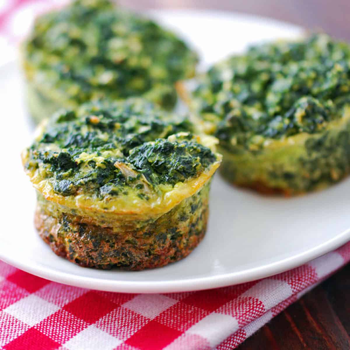 Mini spinach quiches on a white plate.