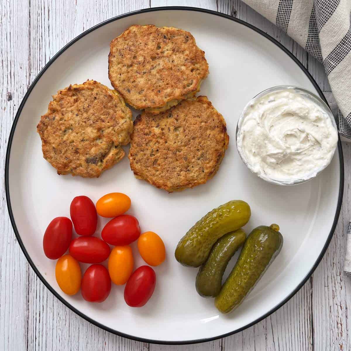 Leftover salmon cakes are served with tomatoes, pickles, and a dip.