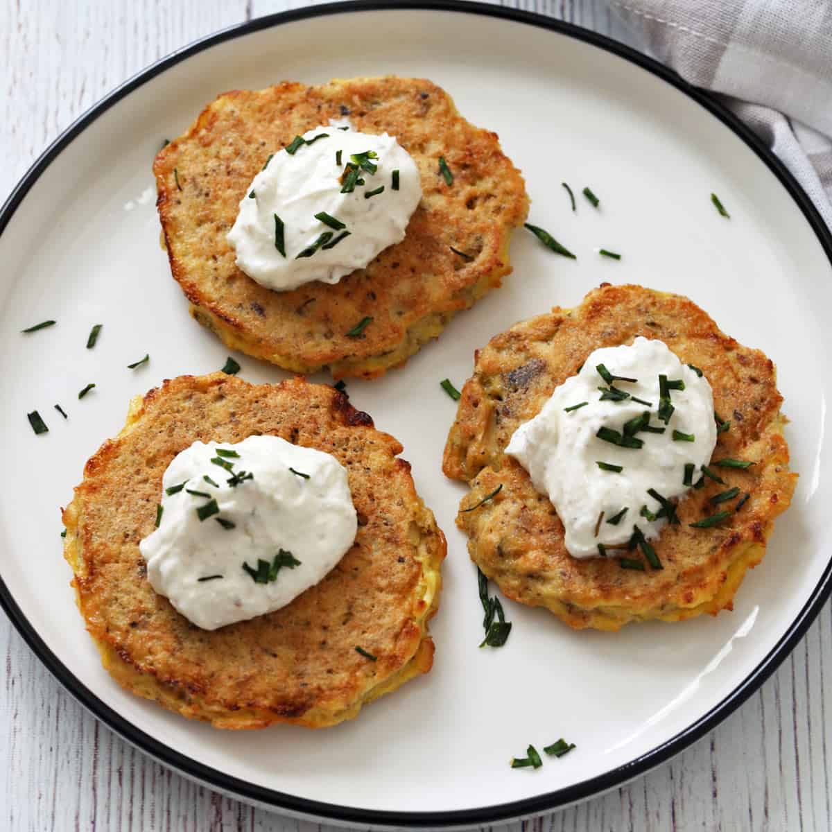 Three salmon cakes are topped with yogurt dip.