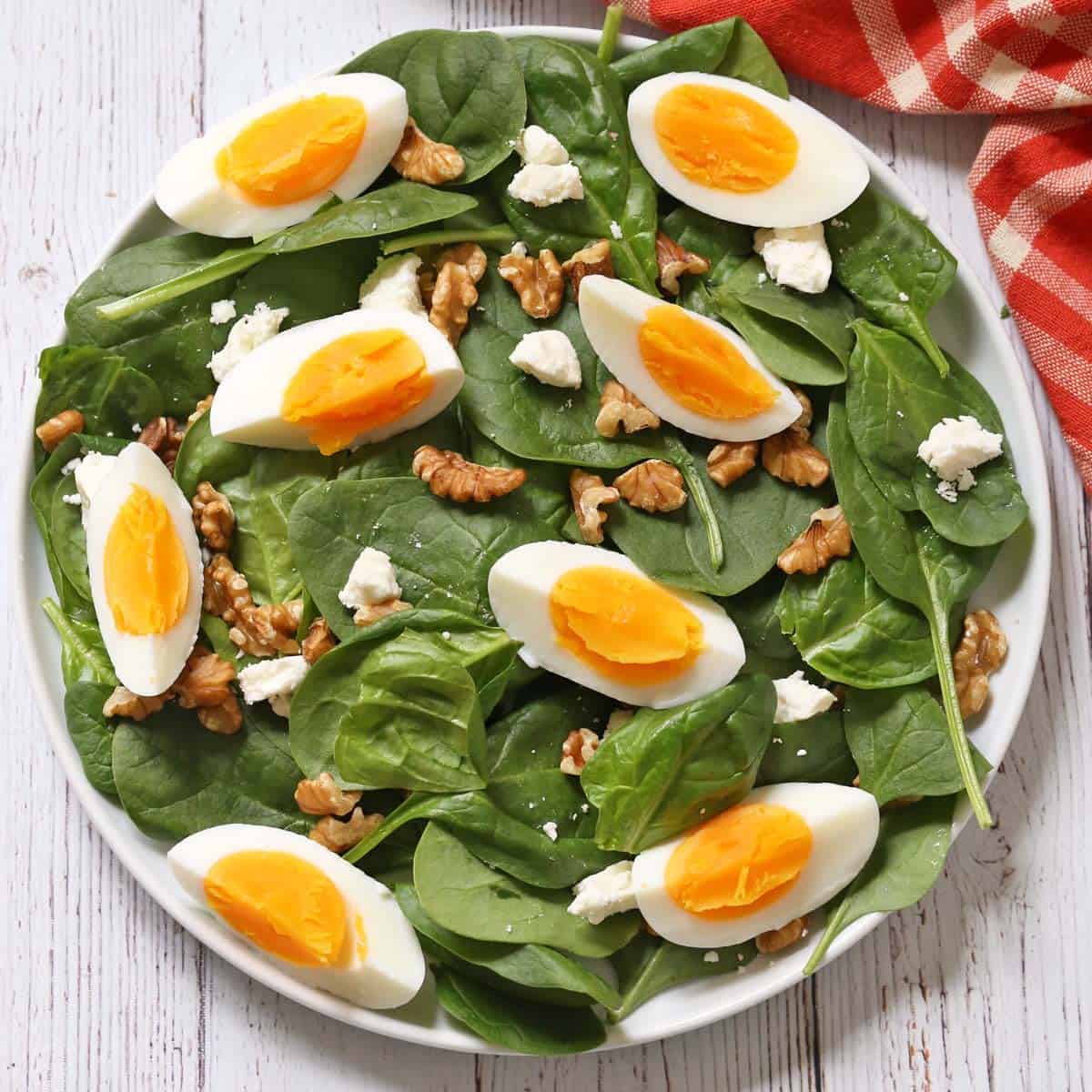Spinach salad is topped with hard-boiled eggs.