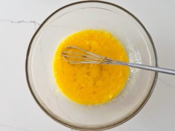 Whisking the eggs, butter, vinegar, and salt.