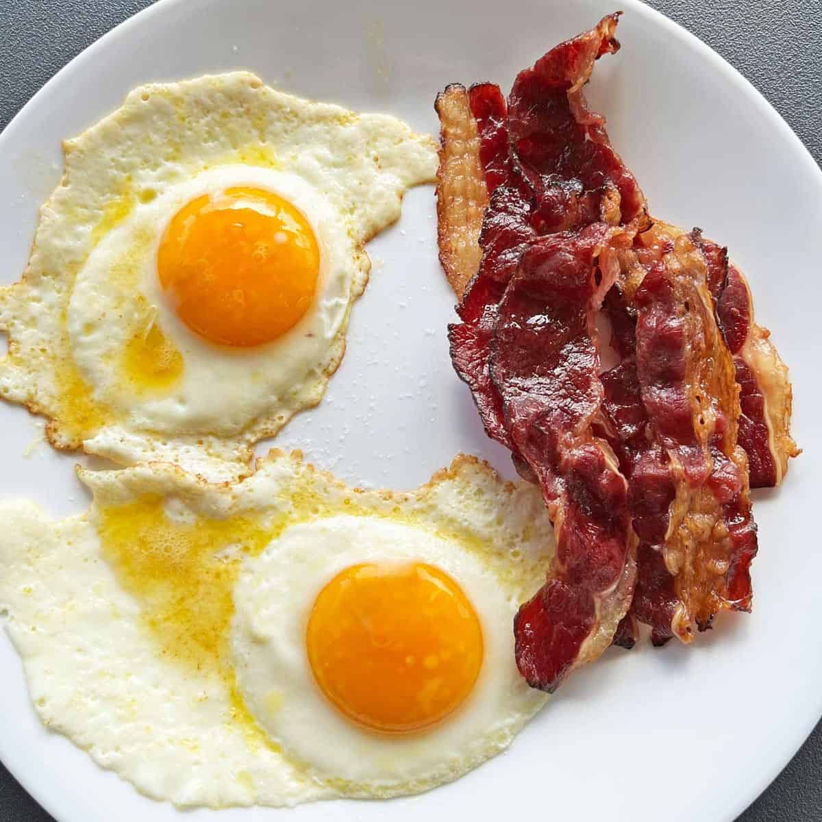 Fried eggs cooked in butter and served with beef bacon.
