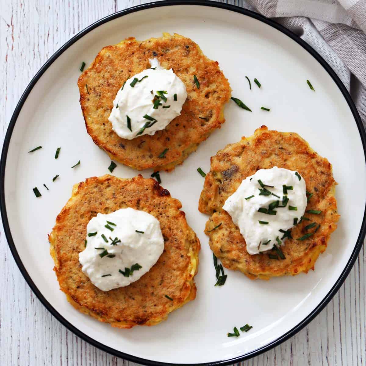 Three salmon cakes are topped with yogurt dip.