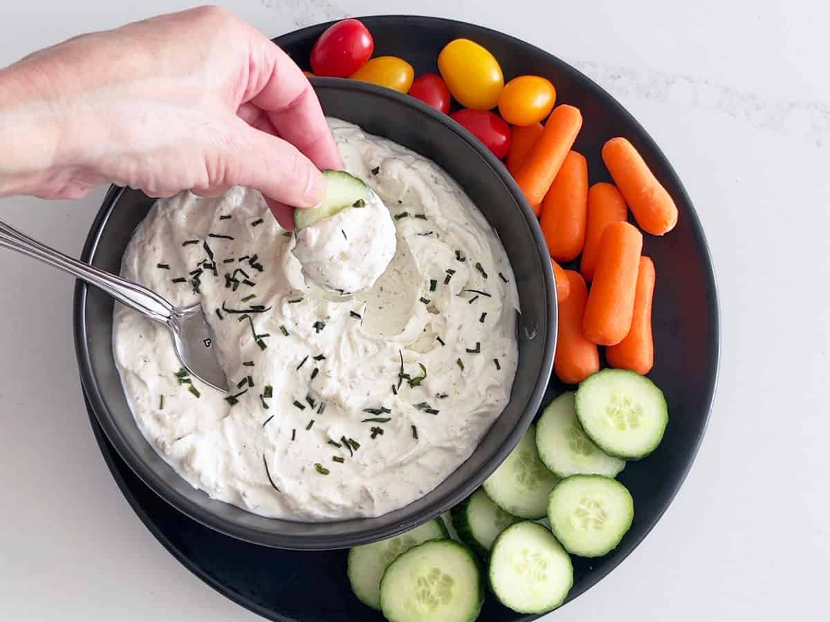 Scooping the dip with a cucumber slice.