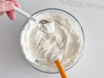 Using a small spoon to taste the dip.