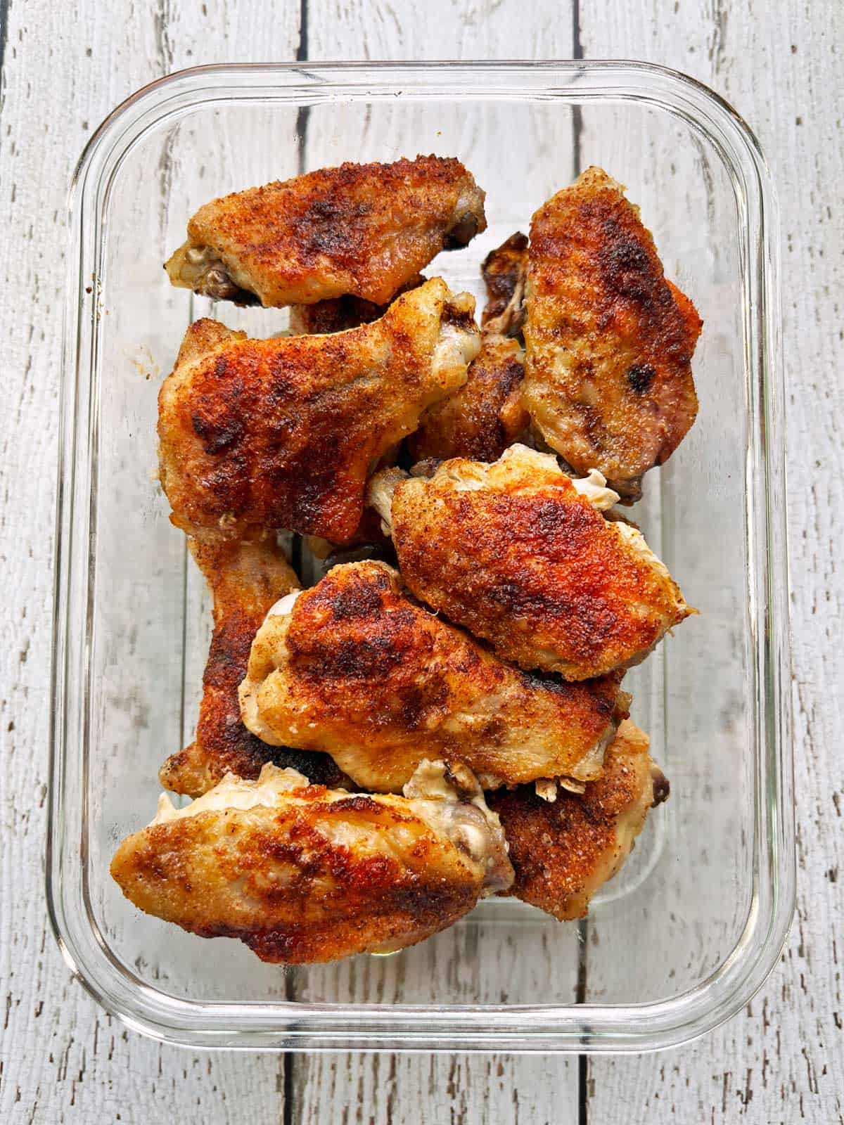 Baked wings are stored in a glass container.