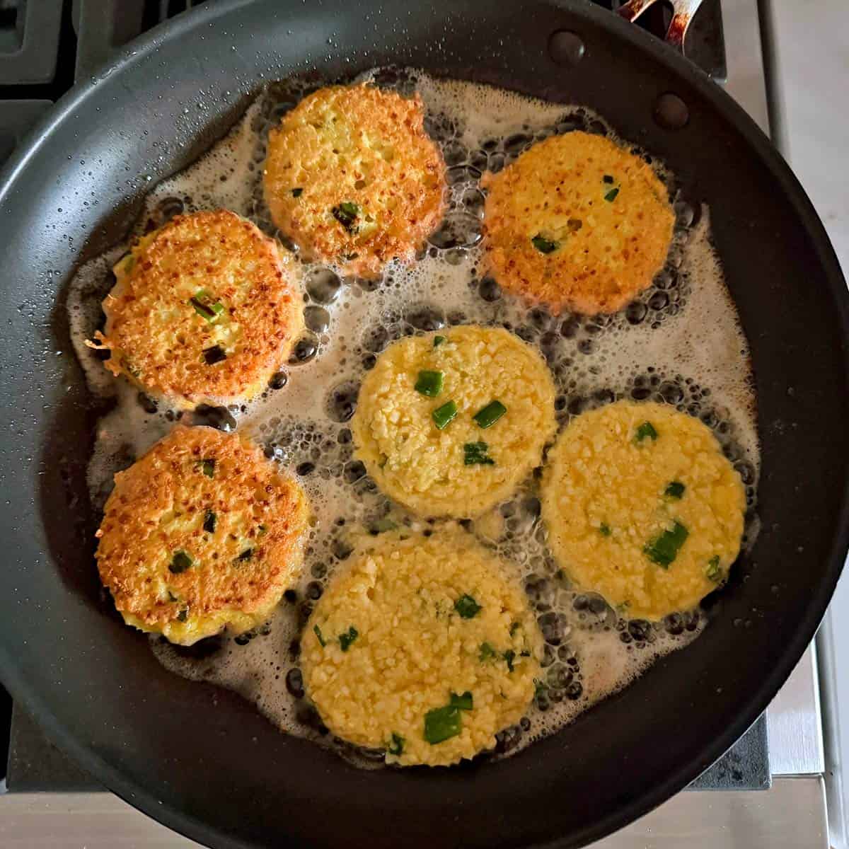 Adding more fritters to the skillet.