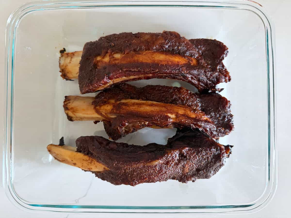Beef back ribs leftovers are stored in a glass container.