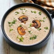 Cream of mushroom soup is served in a dark bowl.