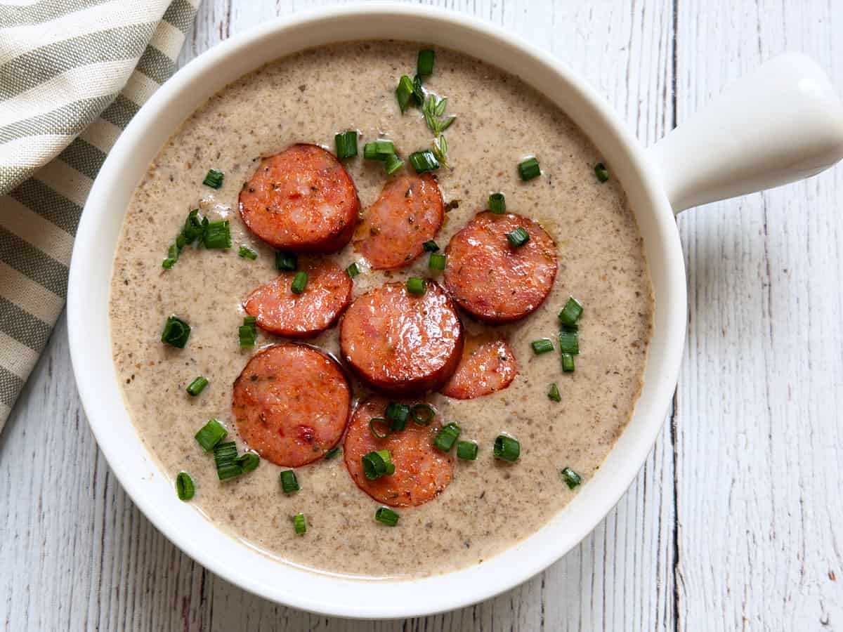 Mushroom soup is topped with sausage slices.
