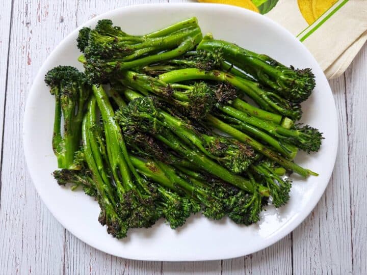Grilled broccolini is served on a white platter.