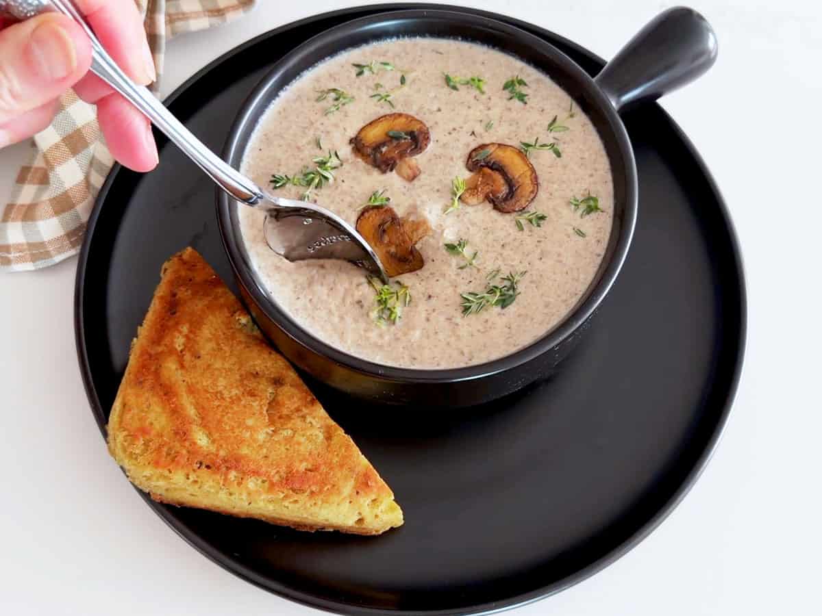 Using a spoon to taste the soup.