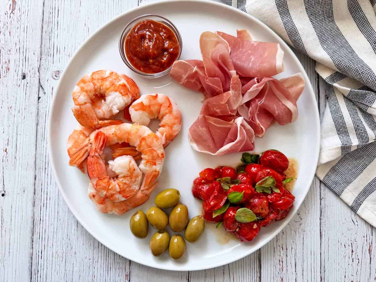Roasted cherry tomatoes are served as a part of an appetizer plate.