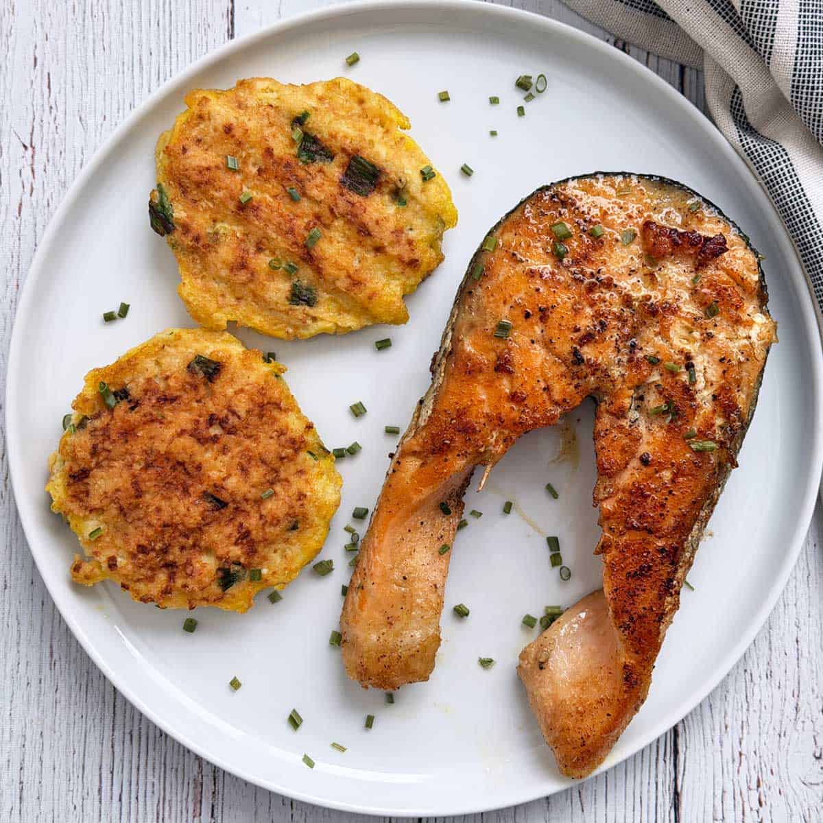 A salmon steak is served with cauliflower fritters.